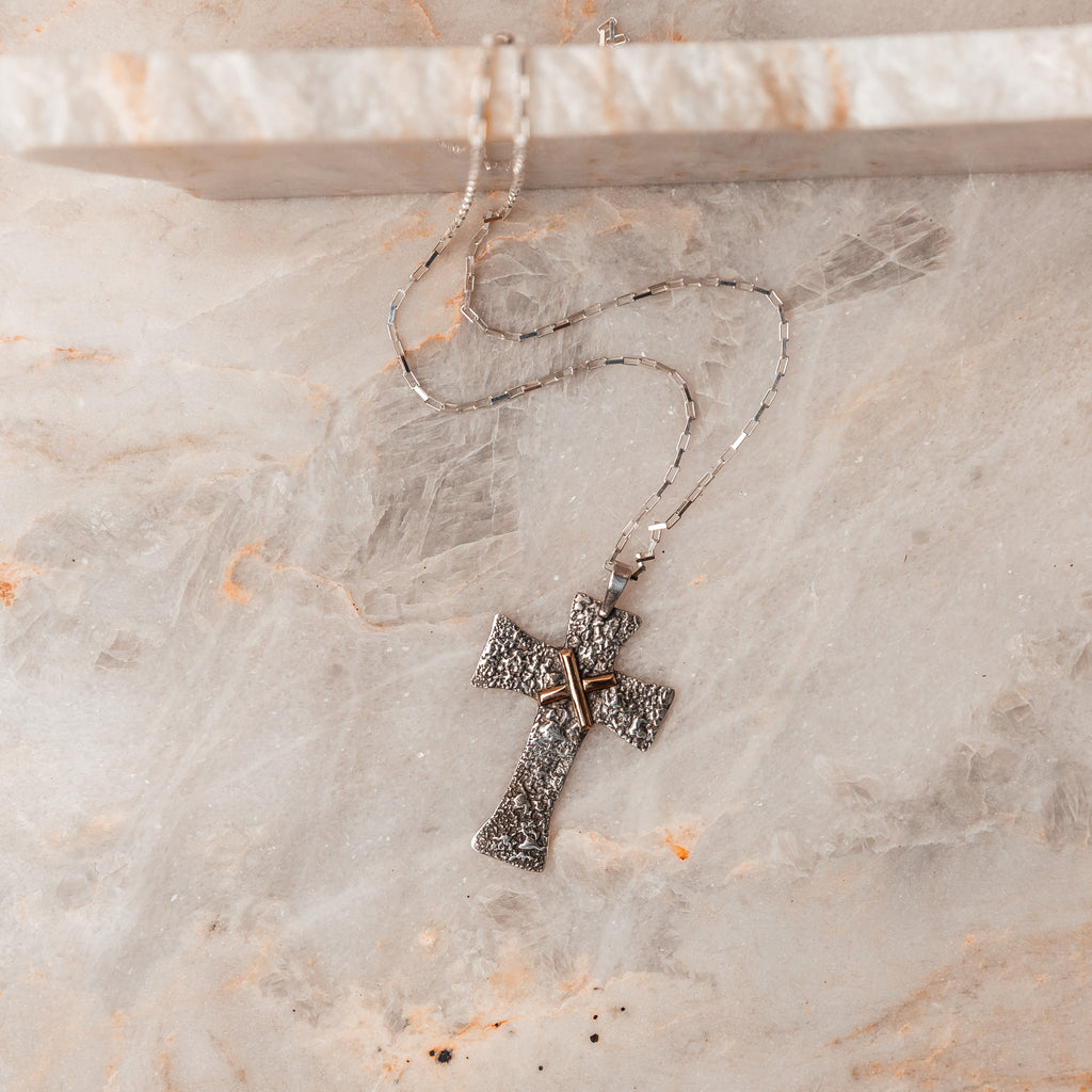 Rugged Elegance - Salome Cross Necklace featuring one-of-a-kind texture from recycled sterling silver dust. Solid gold accent, adjustable chain up to 22 inches. Symbolic of peace