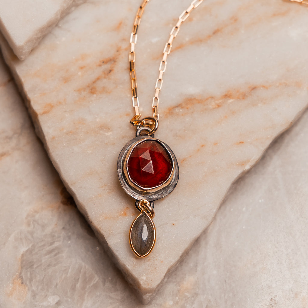 Statement gemstone necklace featuring garnet in a 14k gold bezel and labradorite charm.