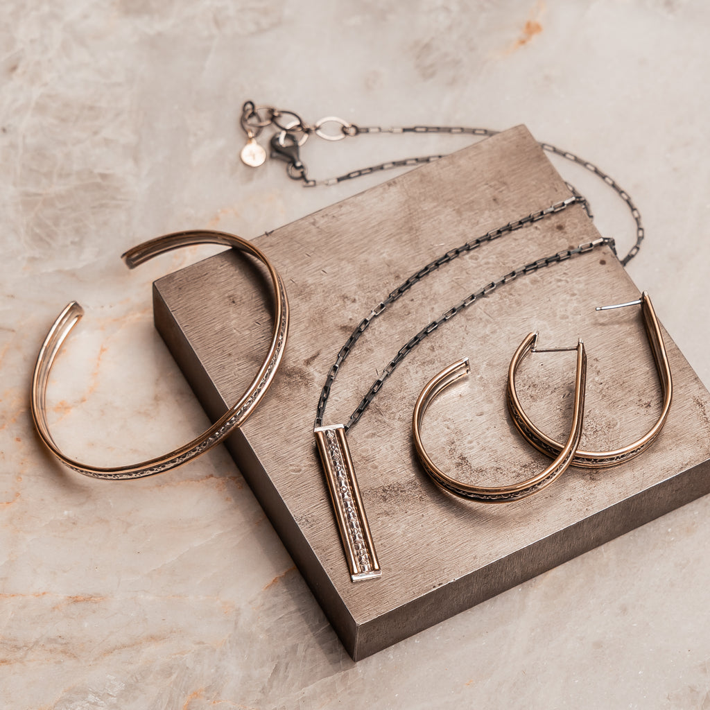 Mixed metal cuff bracelet with textured sterling silver center, ideal for a modern sophisticated look.