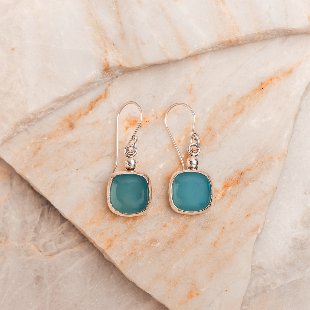 Handcrafted sterling silver earrings with vivid cyan paraiba tourmaline stones.