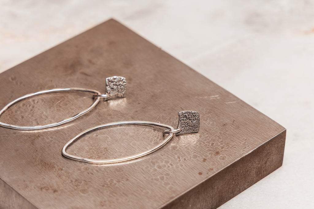 Modern artisan silver hoop earrings with organic texture, handcrafted in sterling silver for a unique boho-chic look.