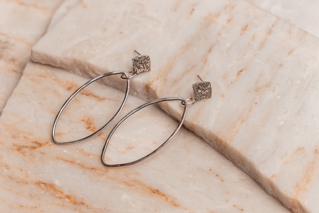 Light-catching handcrafted silver earrings with an organic marquis shape, ideal for modern bohemian outfits.