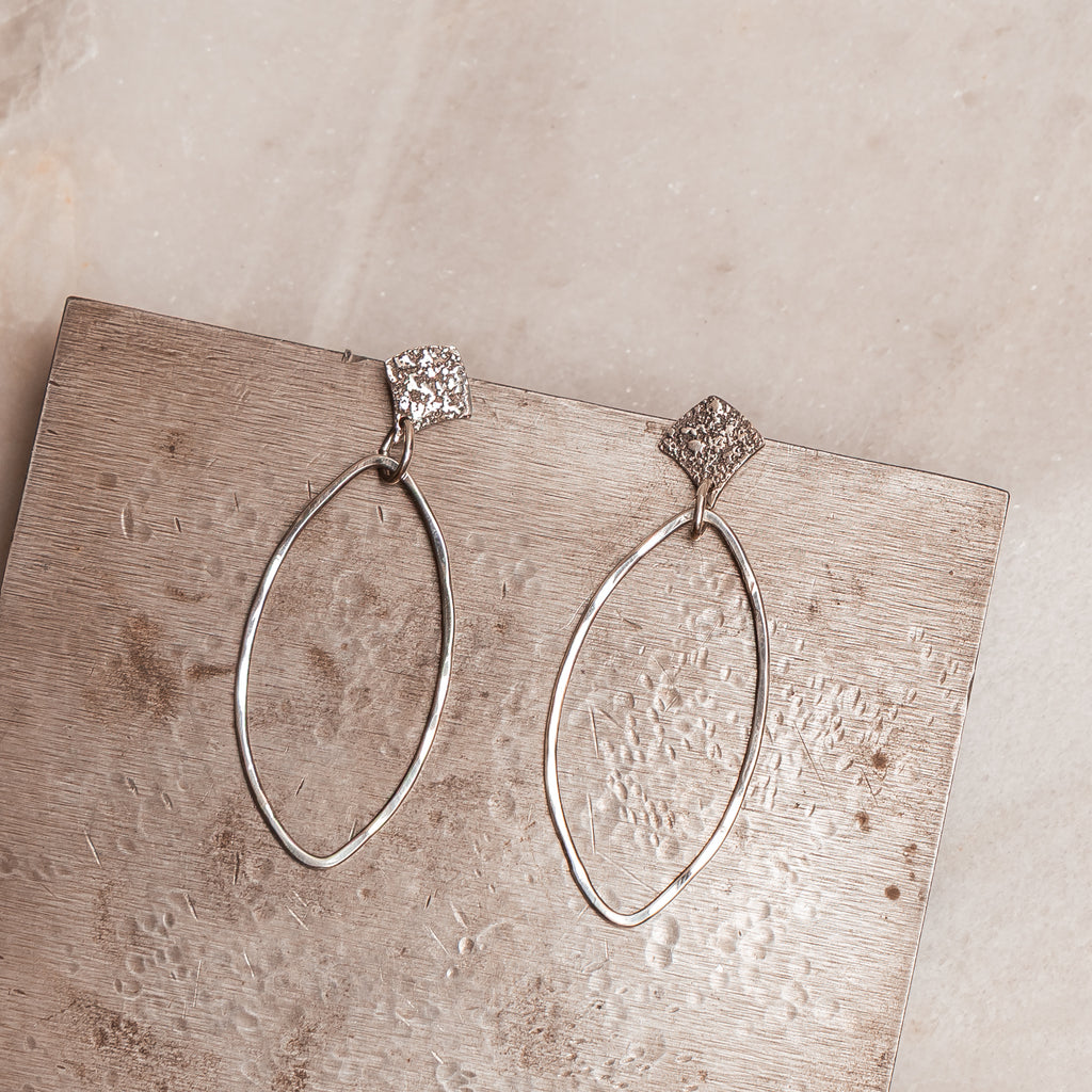 Contemporary silver hoops with a unique fused texture, handcrafted for stylish everyday wear or special occasions.