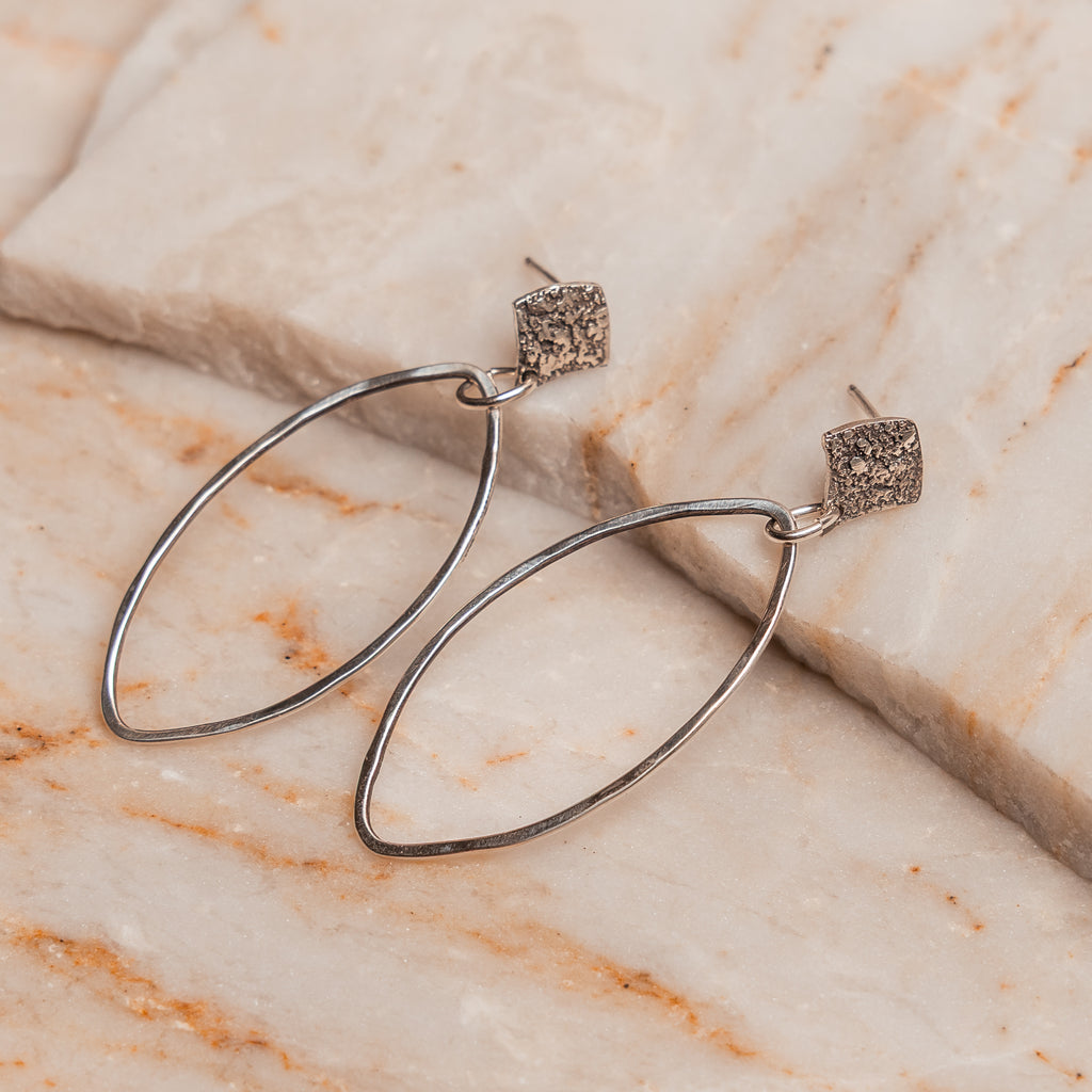 Modern artisan silver hoop earrings with organic texture, handcrafted in sterling silver for a unique boho-chic look.