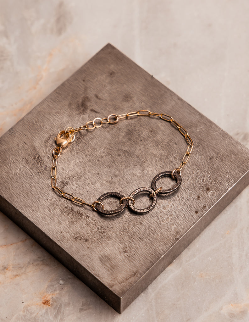 Artisan bracelet with gold filled paperclip chain and hand forged sterling silver rings.