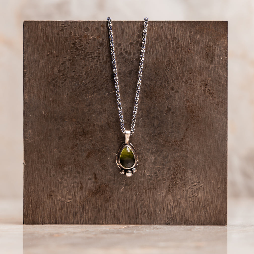 Artisanal sterling silver jewelry showcasing teardrop peridot in botanical design