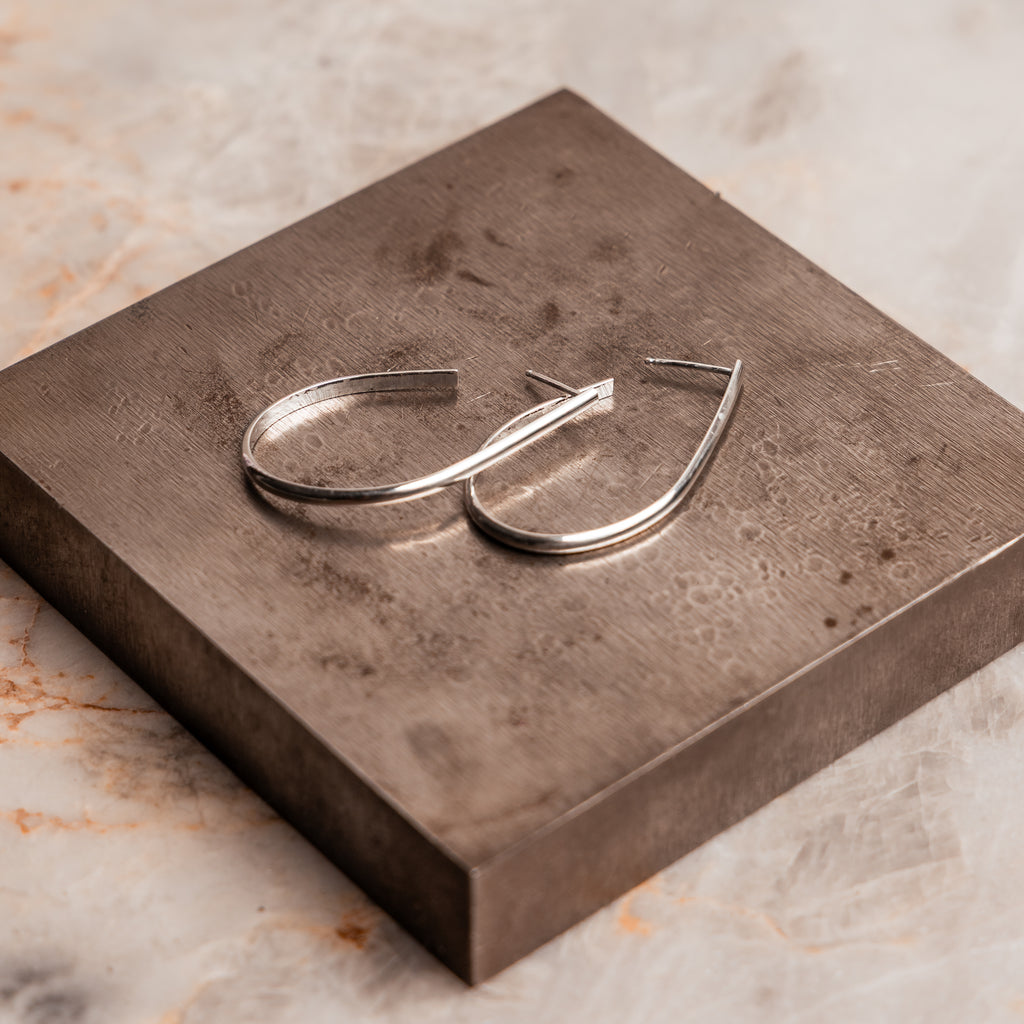Artisan crafted hoop earrings in sterling silver metal, ~1 3/4" long with sterling silver posts, hand forged luxury jewelry.