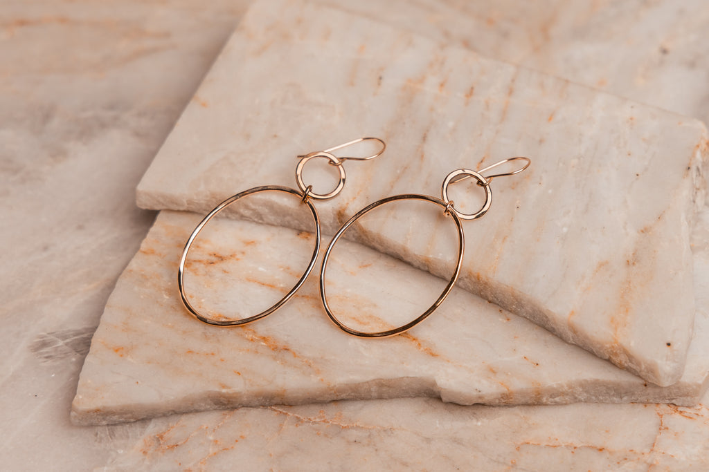Statement earrings featuring two connected gold hoops with textured finish for a handcrafted look