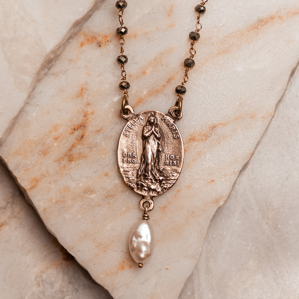 Handmade artisan necklace with meaningful Virgin Mary pendant, adjustable pyrite bead chain, and delicate pearl detail.