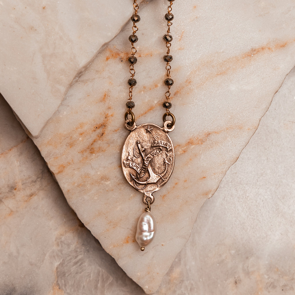 Faith-inspired artisan necklace featuring a hand-cast bronze Virgin Mary pendant and elegant keshi pearl charm on a pyrite beaded chain.