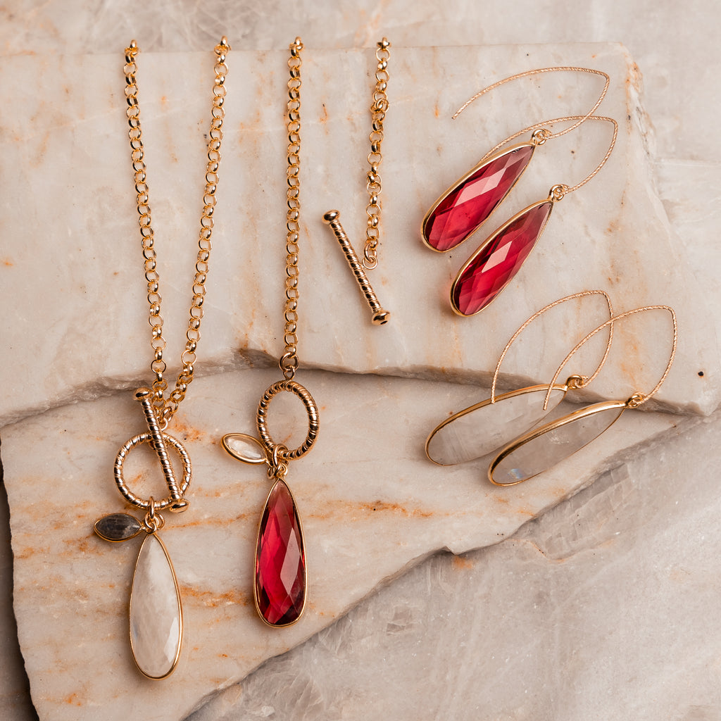 Contemporary gold necklace design featuring teardrop moonstone or red gemstone and front toggle closure